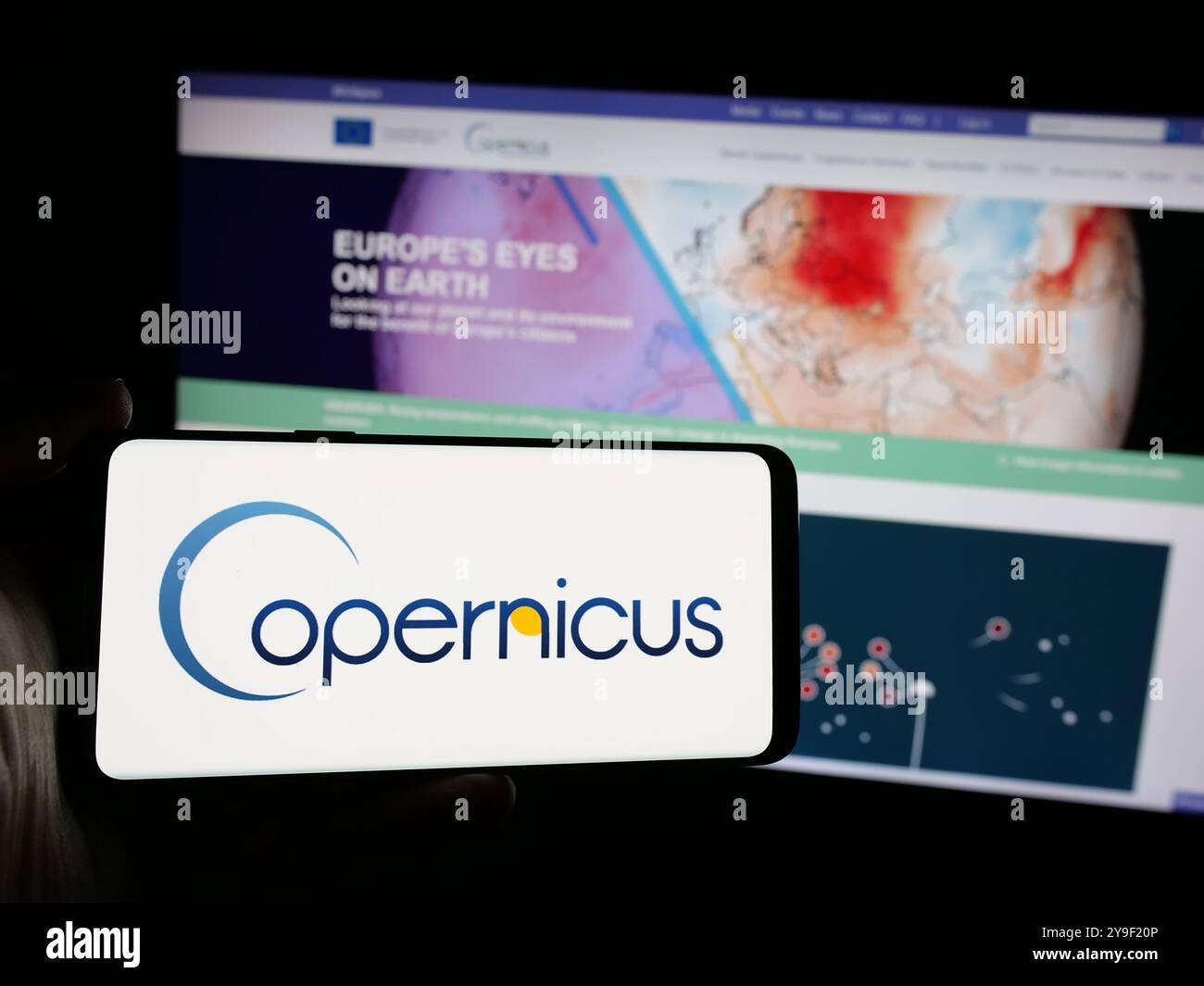 Personne tenant le téléphone portable avec le logo du projet d'observation de la Terre de l'ESA Copernicus sur l'écran en face de la page Web. Concentrez-vous sur l'affichage du téléphone. Banque D'Images