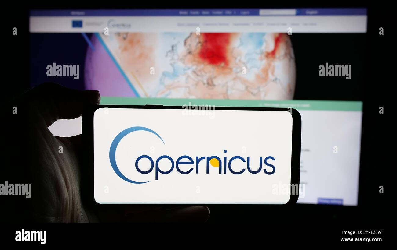 Personne tenant un téléphone portable avec le logo du projet d'observation de la Terre de l'ESA Copernicus sur l'écran en face de la page Web. Concentrez-vous sur l'affichage du téléphone. Banque D'Images