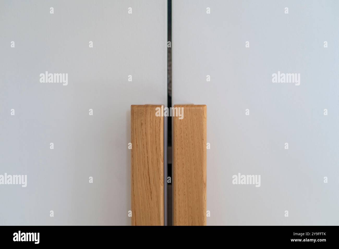 Portes de placard blanches modernes avec poignée en bois, fond de mobilier. Boutons de porte d'armoire en bois Banque D'Images