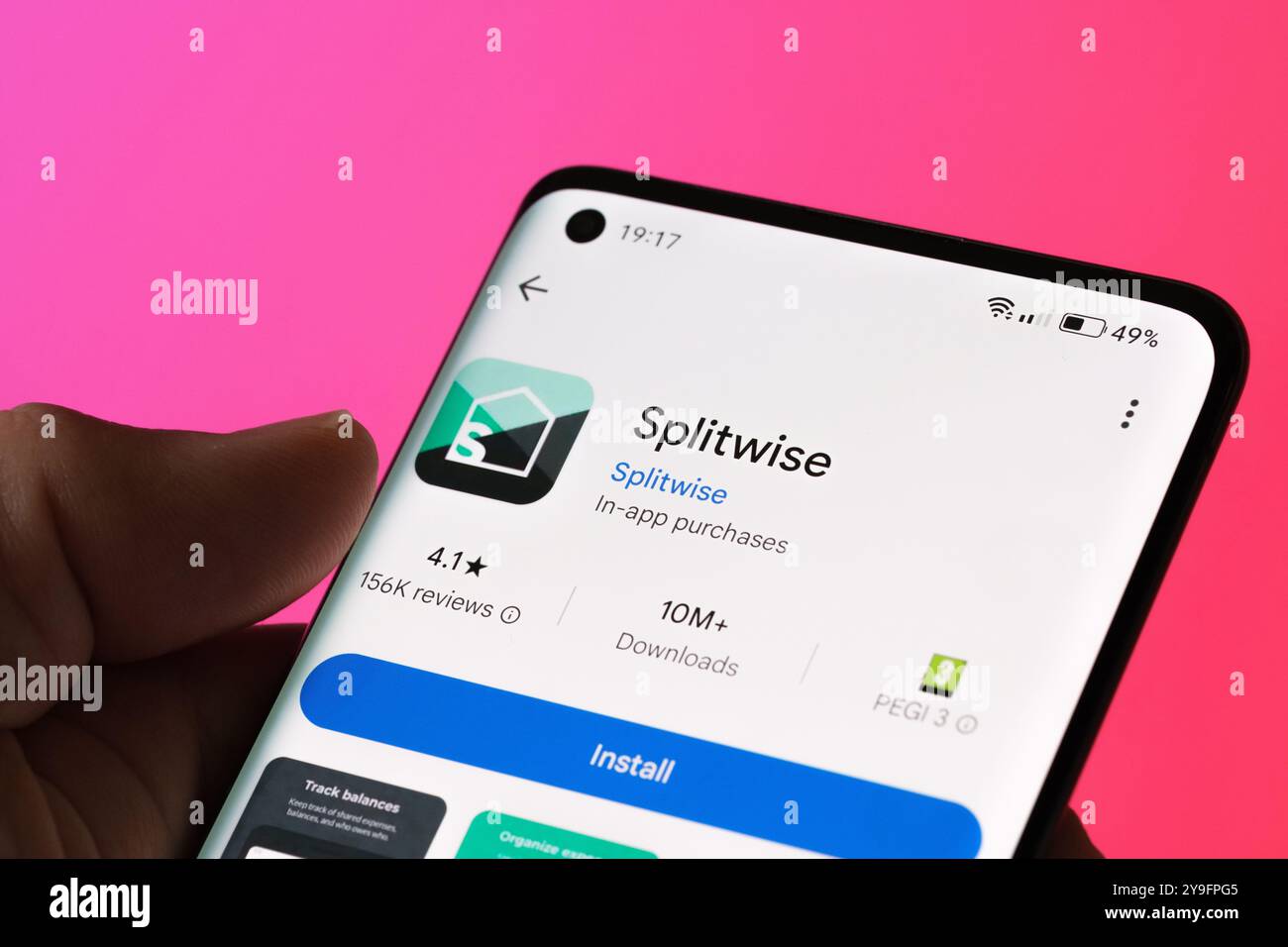 L'écran d'installation de l'application Splitwise s'affiche sur un smartphone, avec des outils pour fractionner les dépenses et suivre les factures partagées. Backgrou rose vif Banque D'Images