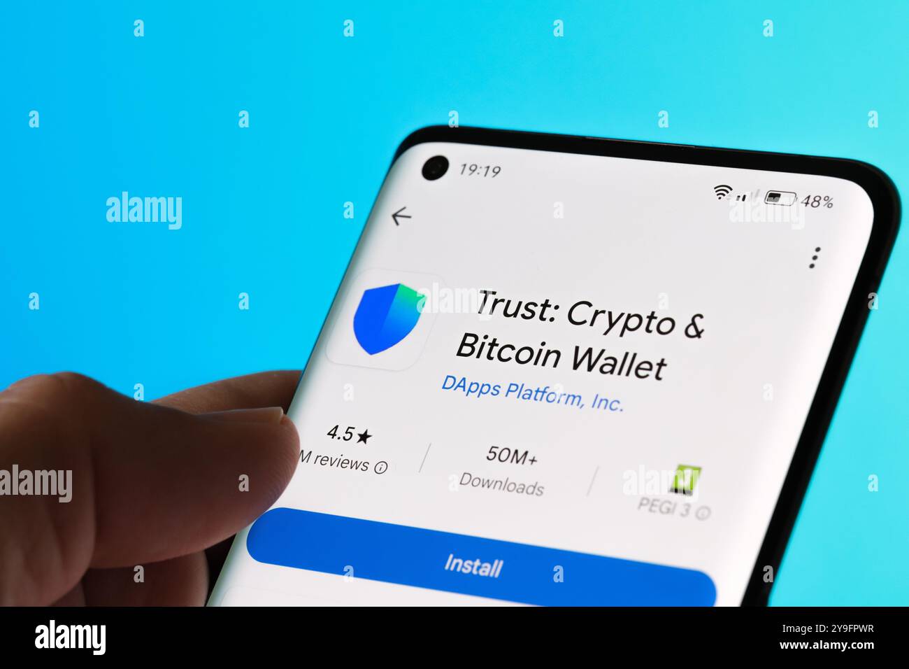 Application Trust Wallet présentée sur un smartphone, offrant des services pour le stockage sécurisé de crypto-monnaie et les transactions Bitcoin. Fond bleu vif. Stafford Banque D'Images