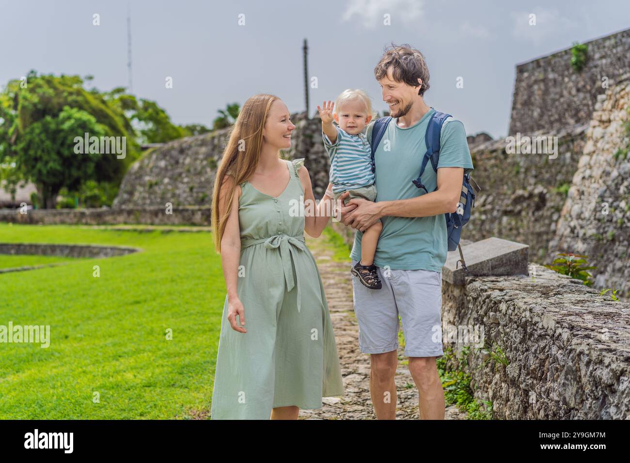 Maman, papa et leur bébé fils explorant Fuerte de San Felipe de Bacalar. Voyage en famille, patrimoine culturel et concept d'aventure historique Banque D'Images