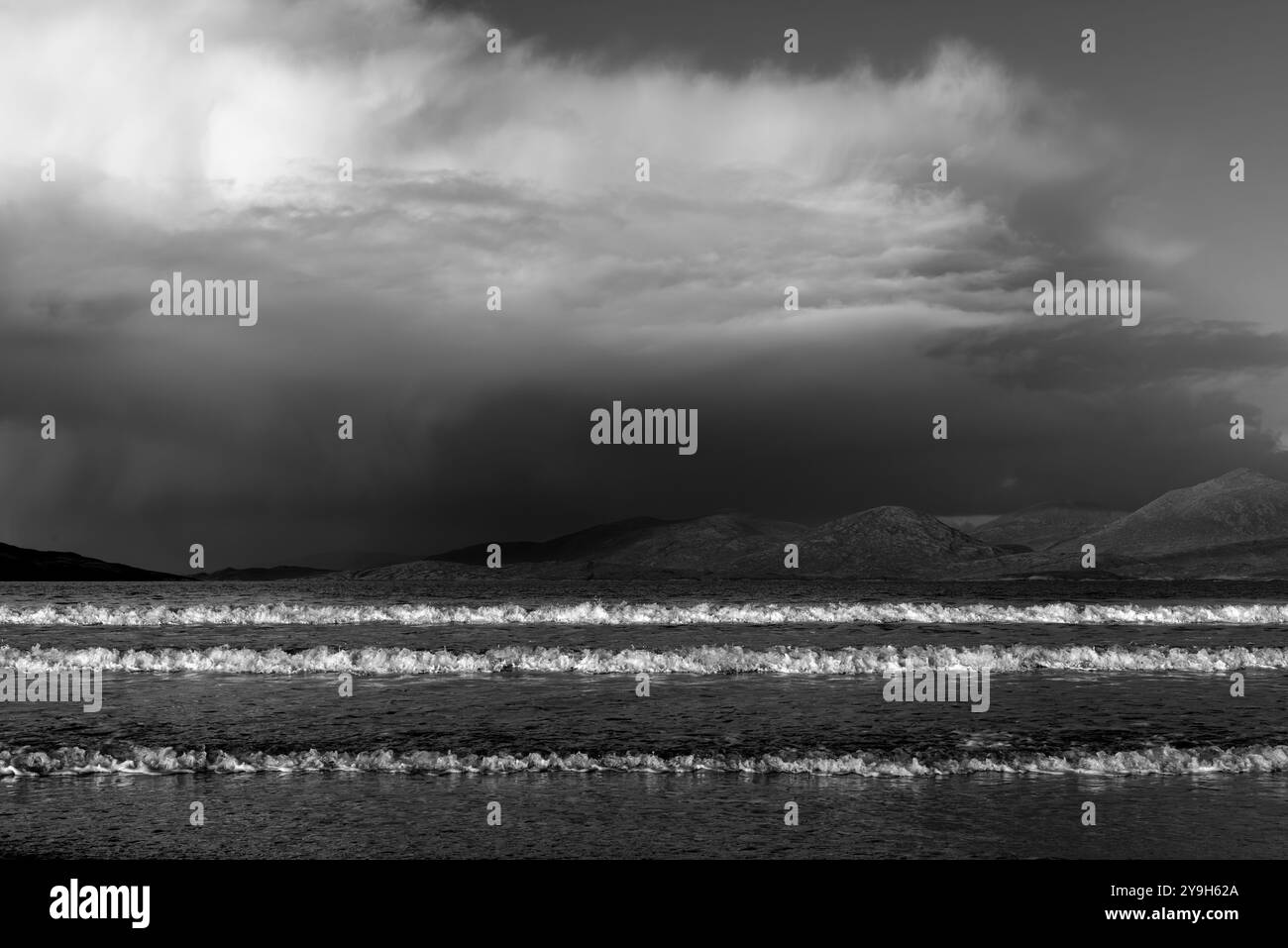 Les vagues s'écrasent sur les rives de la plage de Lusketyre alors qu'une tempête roule sur les collines de l'île de Taransay , créant une scène côtière spectaculaire. Banque D'Images