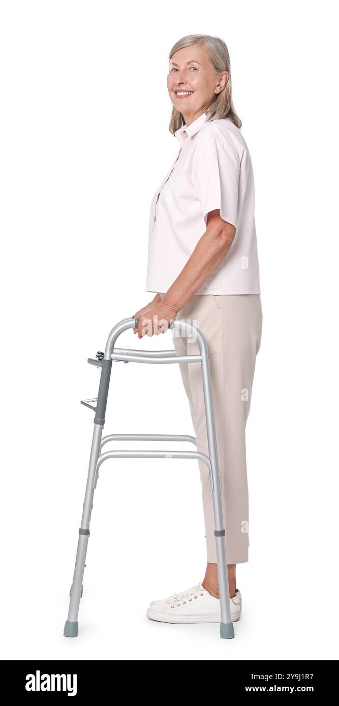 Femme senior utilisant le cadre de marche sur fond blanc Banque D'Images