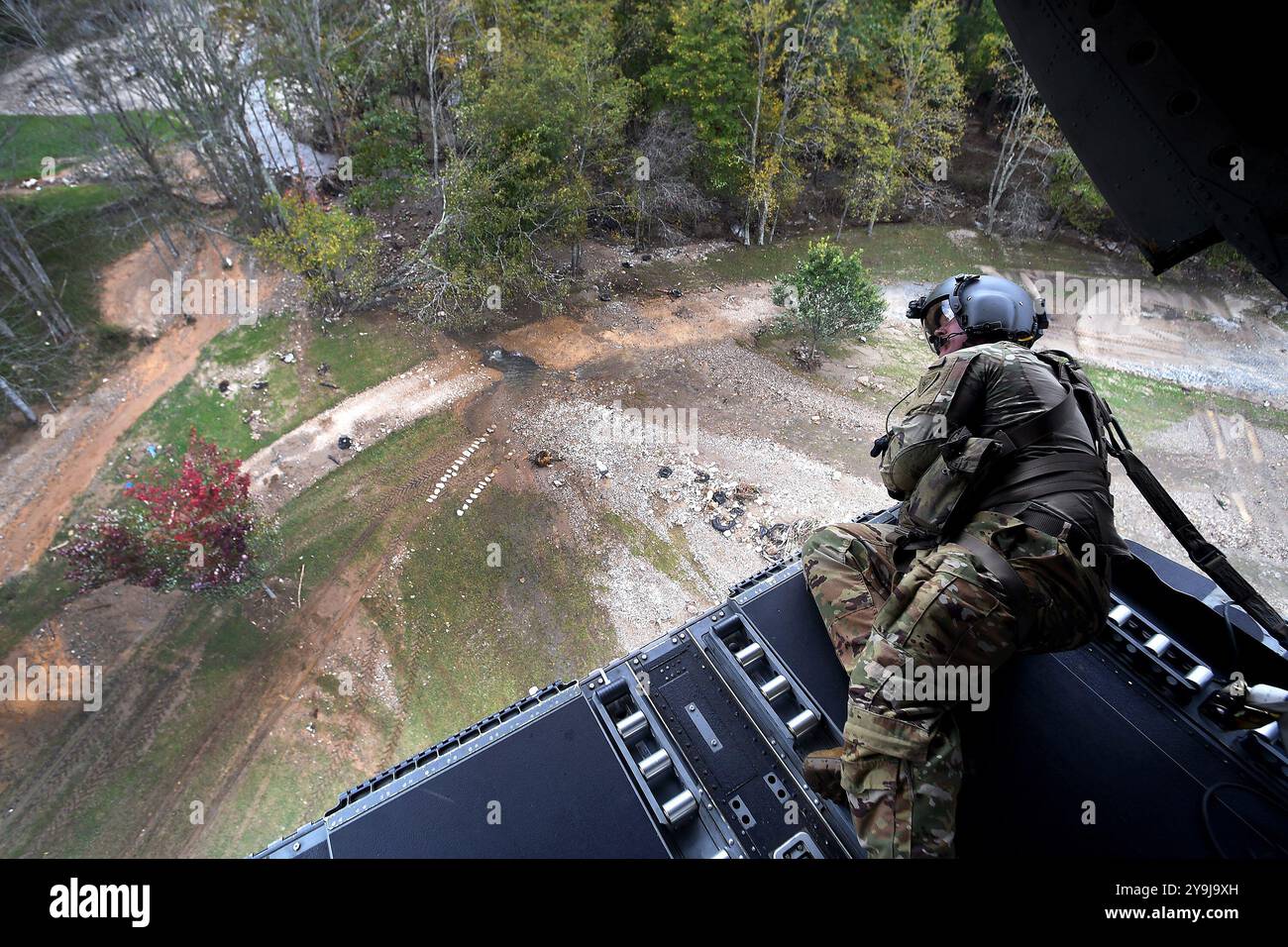 WESTERN, Caroline du Nord, États-Unis. 4 octobre 2024. Le sergent Derick Bauman, ingénieur de vol de la compagnie B, 2nd Battalion, 238th Aviation Regiment, Ohio Army National Guard surveille les obstacles de la rampe arrière d'un hélicoptère CH-47 Chinook lors de l'atterrissage dans un champ pour distribuer de la nourriture, de l'eau et d'autres fournitures aux communautés de l'ouest de la Caroline du Nord à la suite de l'ouragan Helene, en octobre. 4, 2024. Les unités de la Garde nationale de 17 états ont réagi dans les zones touchées par la tempête et ont participé à la distribution de nourriture et d'eau, à la recherche et au sauvetage, au déblaiement des débris A. Banque D'Images