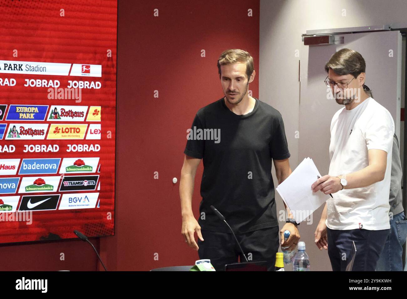 Avec le porte-parole de presse Sascha Glunk (à gauche), l’entraîneur-chef Julian Schuster (SC Freiburg) entre dans la salle de presse pour la première fois après le départ O. Banque D'Images