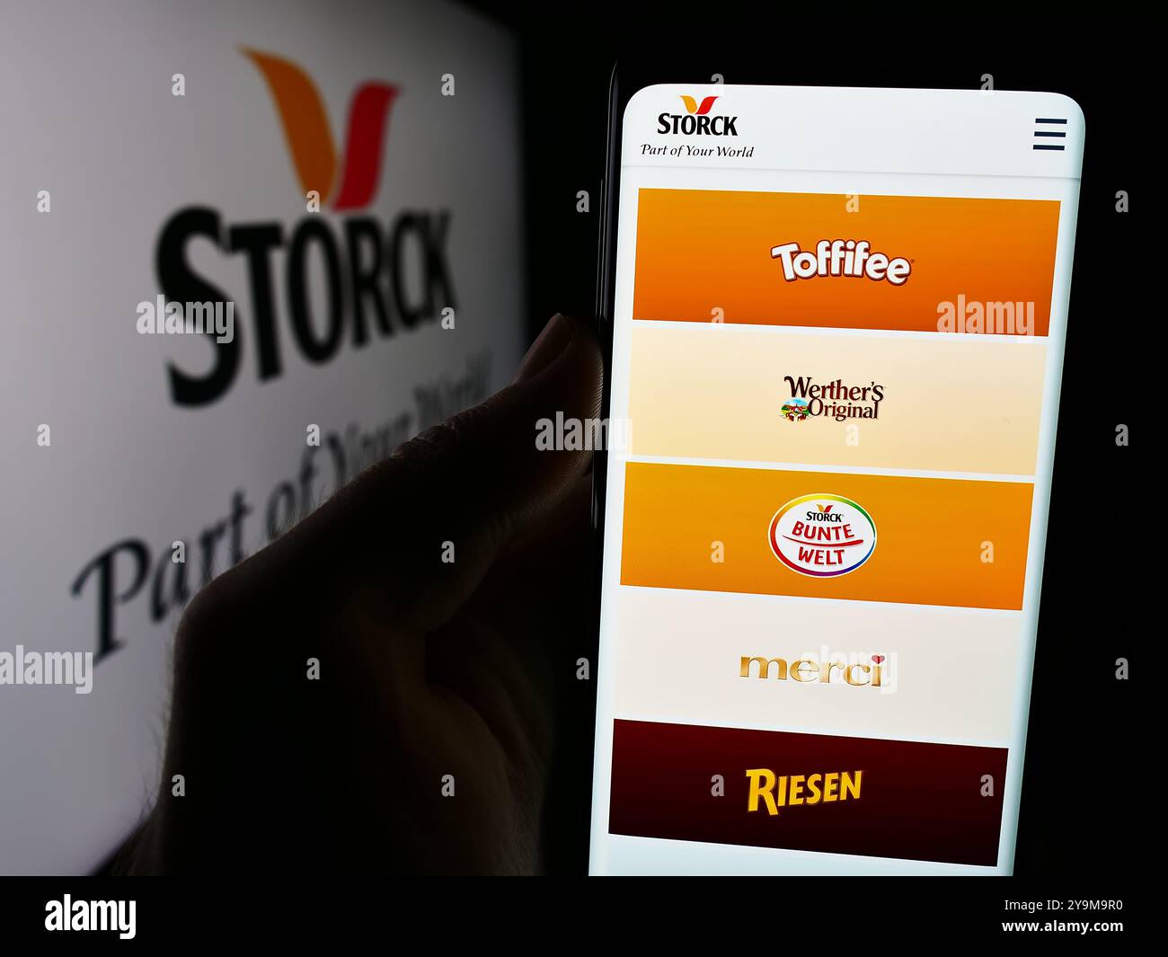 Dans cette illustration photo, une personne tient un smartphone avec la page Web de la société allemande de confiserie August Storck KG devant le logo. Banque D'Images