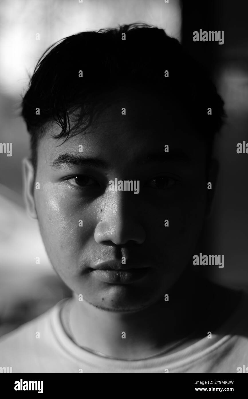 Un homme d'Asie du Sud-est regardant la caméra sans expression avec un arrière-plan flou. Gros plan et vue de la tête. Photogra mode noir et blanc Banque D'Images