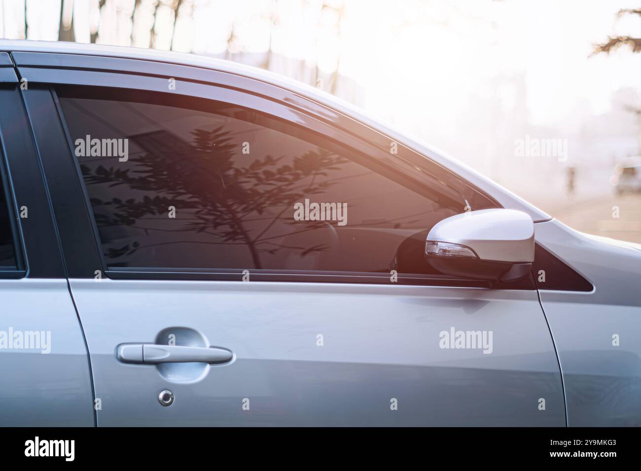 Une voiture aux vitres teintées reflète la lumière du soleil rougeâtre Banque D'Images