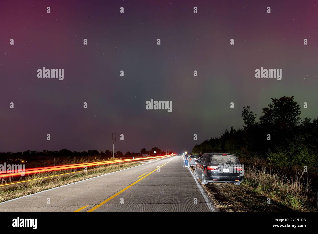 Sperry, Iowa, États-Unis. 10 octobre 2024. Des voitures se sont arrêtées devant l'Observatoire Witte à Sperry, Iowa, USA dans la nuit du 10 octobre 2024 avec des gens regardant les aurores boréales. Une voiture de passage traîne dans une photo de longue date. Crédit : Keith Turrill/Alamy Live News. Banque D'Images