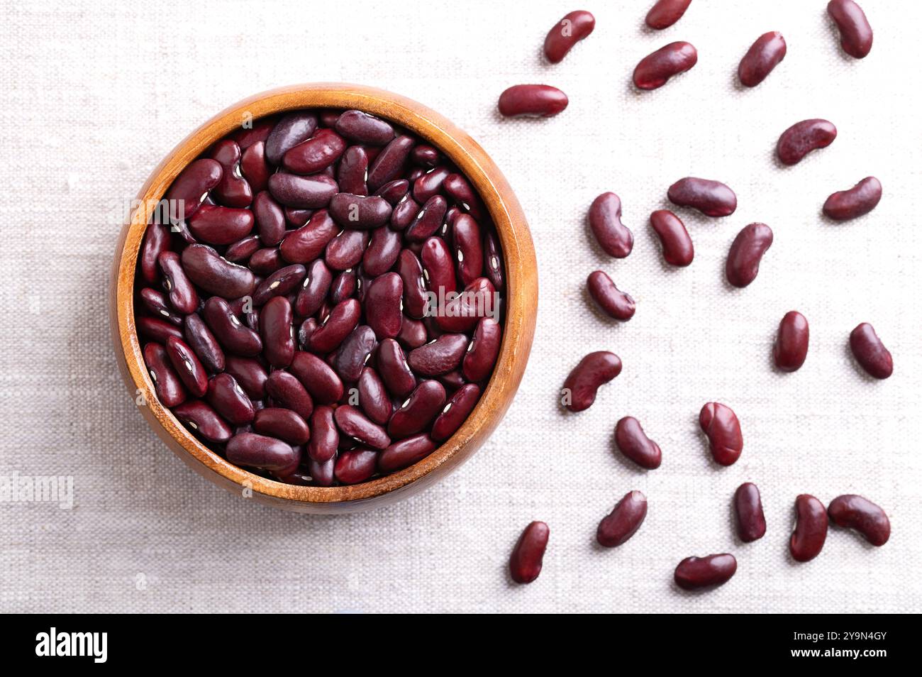 Haricots rouges séchés dans un bol en bois sur tissu de lin. Haricots communs crus, non cuits, une variété du haricot commun Phaseolus vulgaris. Banque D'Images