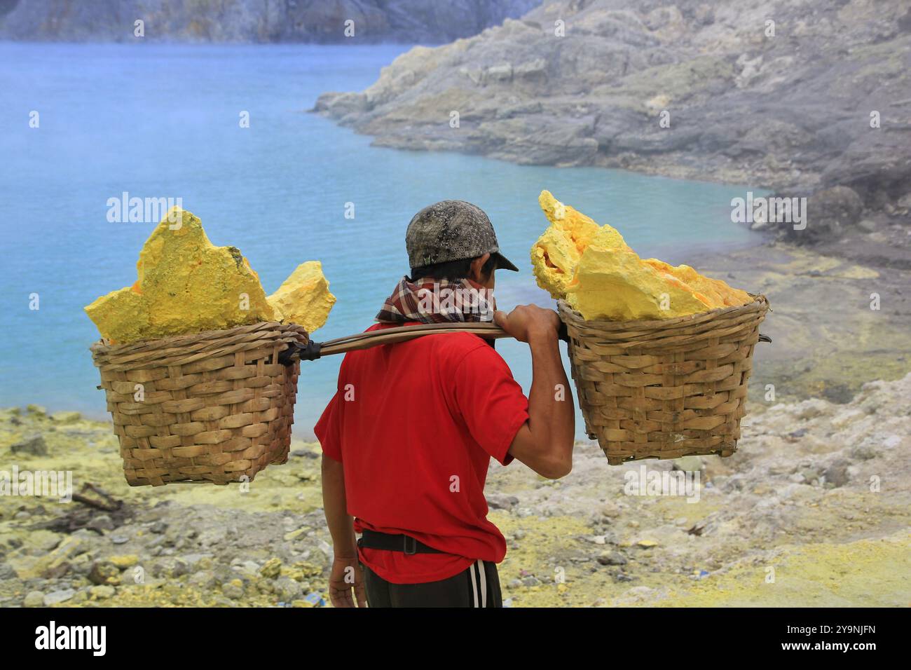 Mineur de soufre dans le cratère Ijen transportant des produits miniers de soufre pesant en moyenne 90 kilogrammes. Banque D'Images