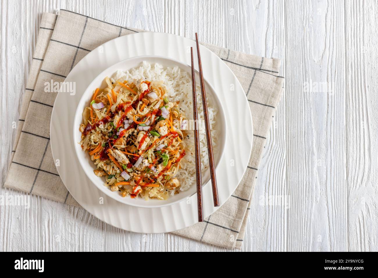 roulé aux œufs de tofu, chou sautés, tofu émietté assaisonné servi dans une sauce sucrée et salée servie sur du riz dans un bol sur une table en bois blanc avec des côtelettes Banque D'Images