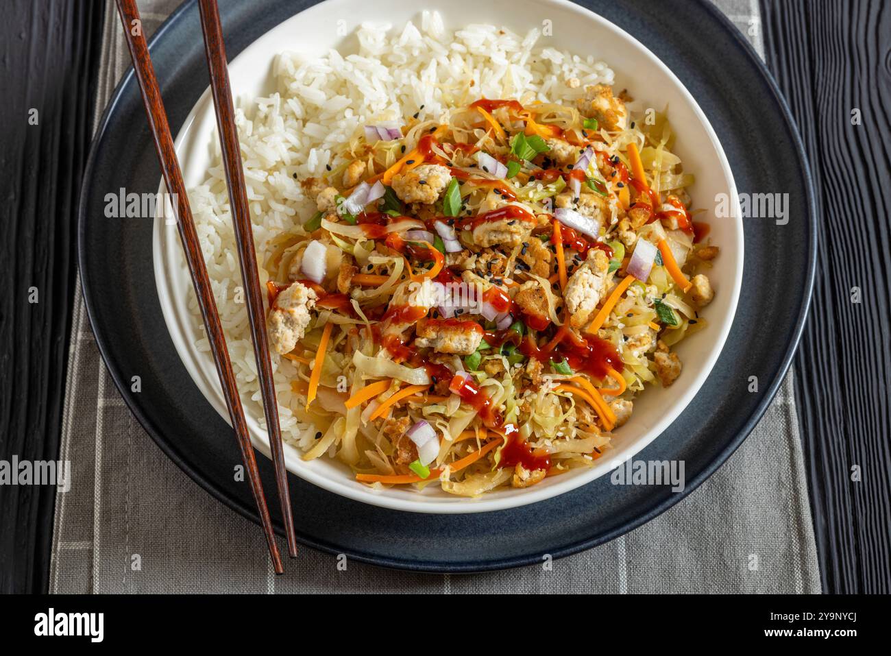 roulé aux œufs de tofu, chou sautés, tofu émietté assaisonné servi dans une sauce sucrée et salée servi sur du riz dans un bol sur une table en bois noir avec des côtelettes Banque D'Images