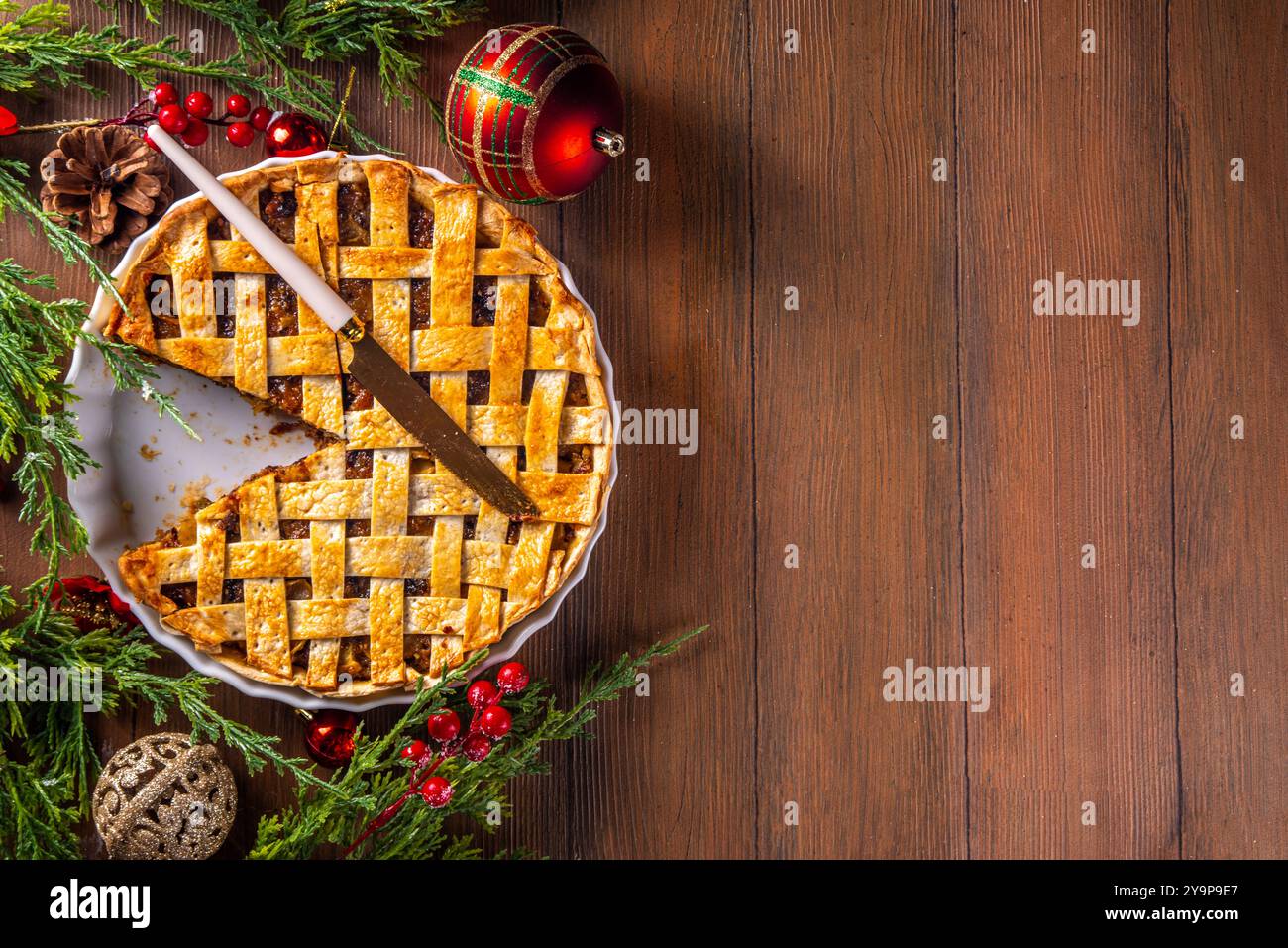 Tarte de Noël britannique traditionnelle. Gâteau à la tarte au mincemeat sucré maison, rempli de fruits secs épicés, de noix et de pommes, sur une table en bois confortable Wit Banque D'Images