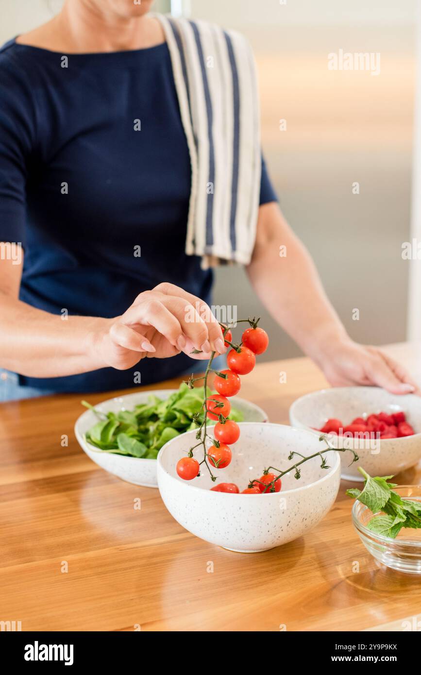 Femme tenant la vigne de tomates cerises Banque D'Images
