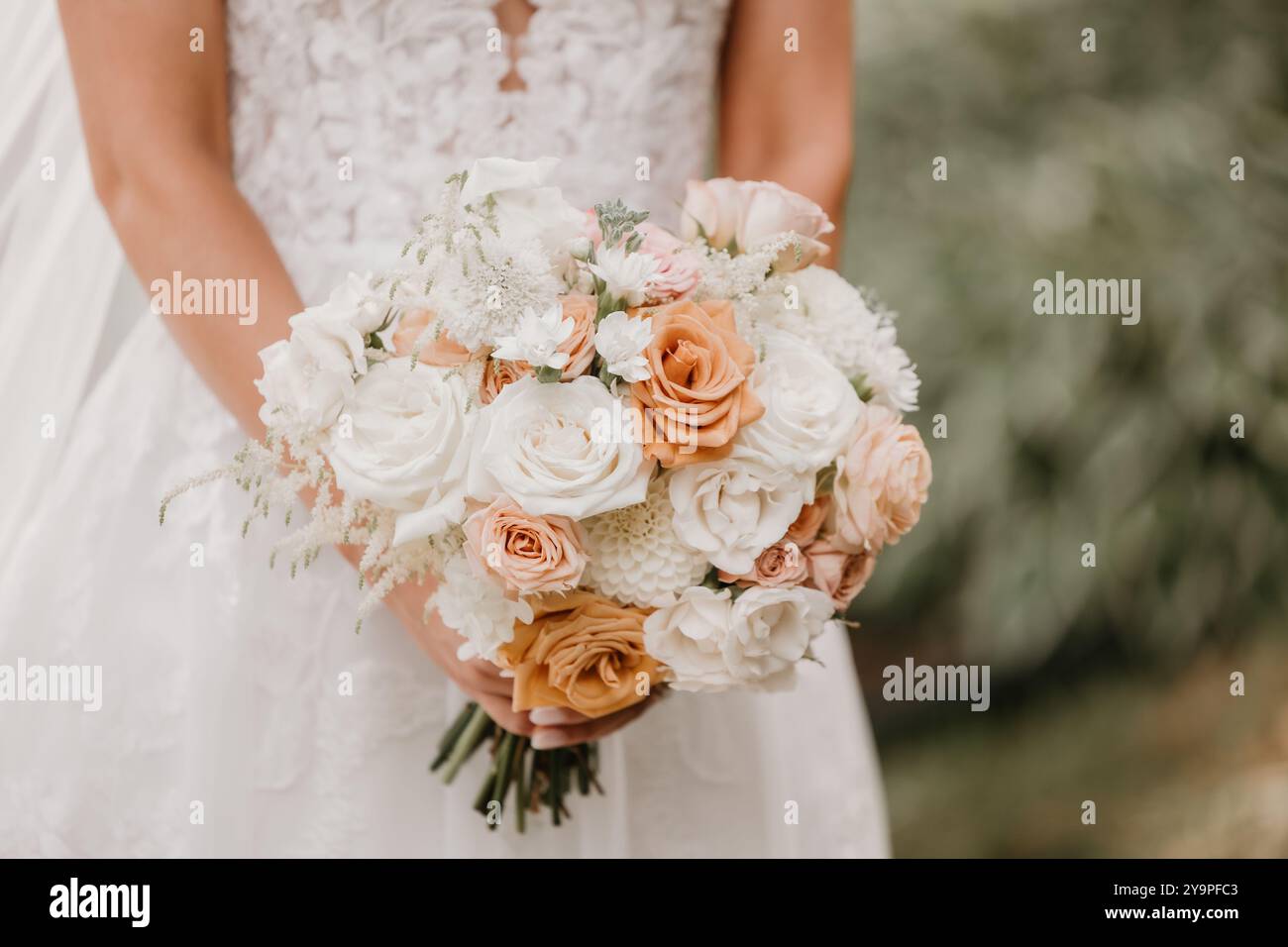 Mariée dans une robe de mariée en dentelle tenant un bouquet Banque D'Images