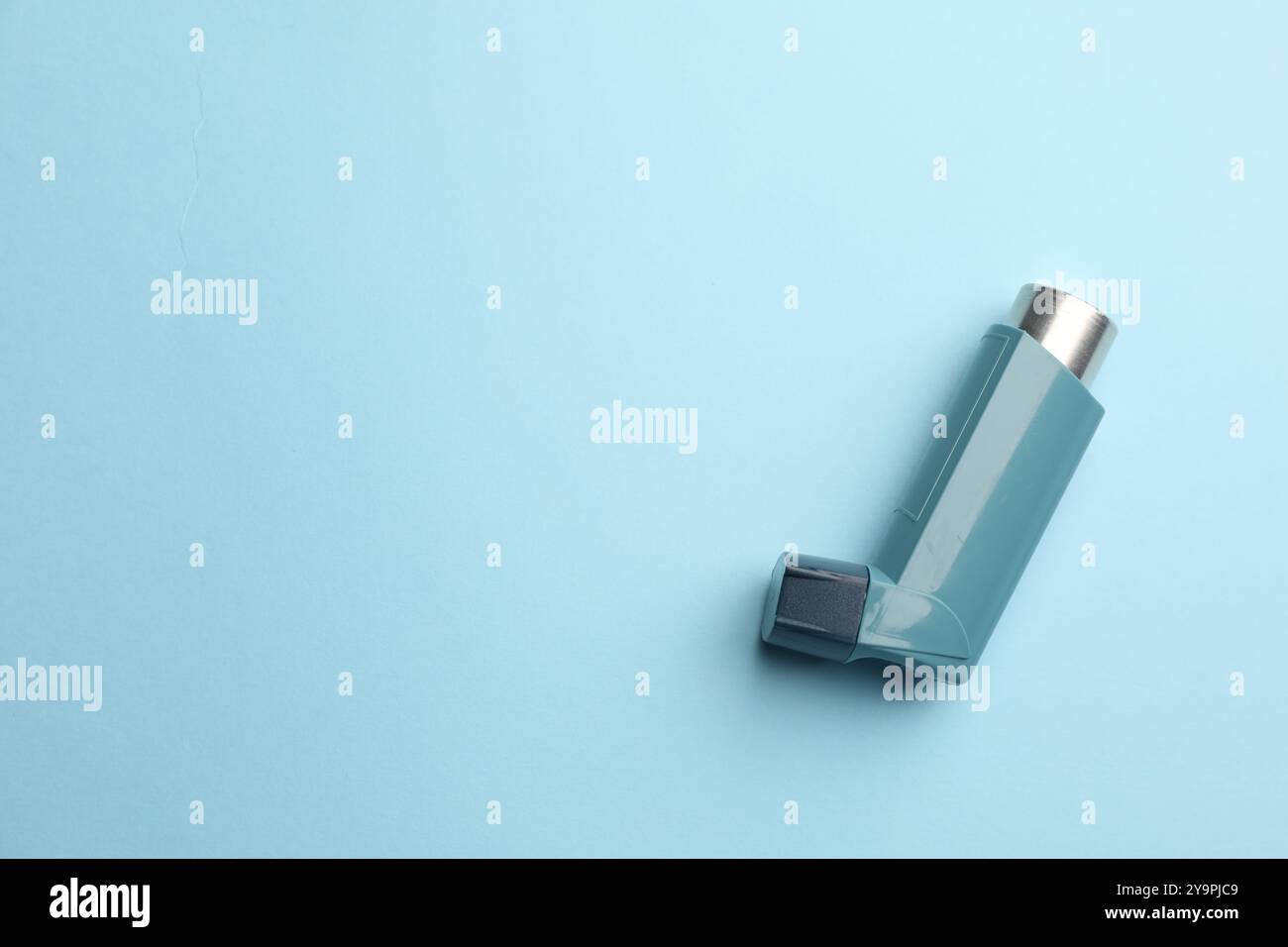 Inhalateur d'asthme sur fond bleu clair, vue de dessus. Espace pour le texte Banque D'Images