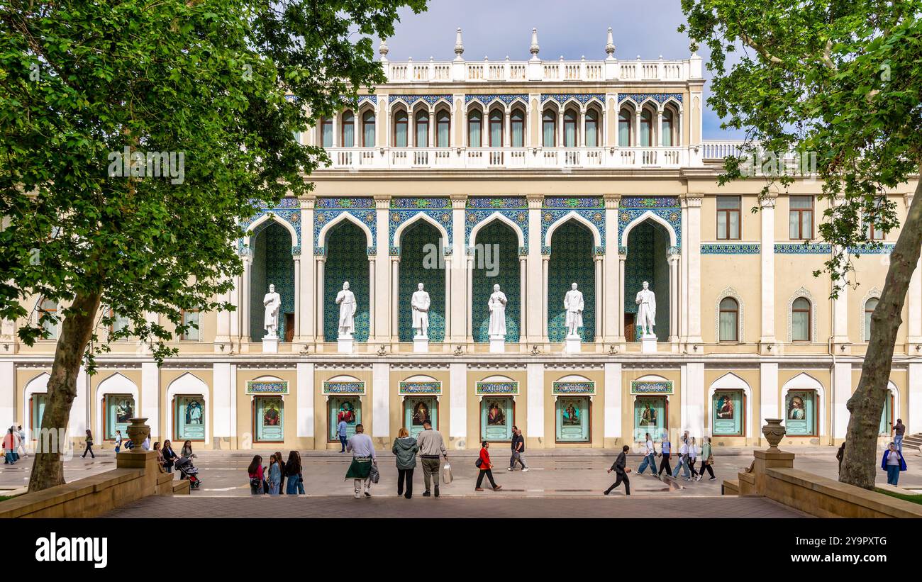 Bakou, Azerbaïdjan - 5 mai 2024 : Musée Nizami d'Azerbaïdjan, avec des statues bordant la façade. Le bâtiment est décoré avec des arches et des carreaux complexes. On peut voir des gens marcher près du bâtiment Banque D'Images