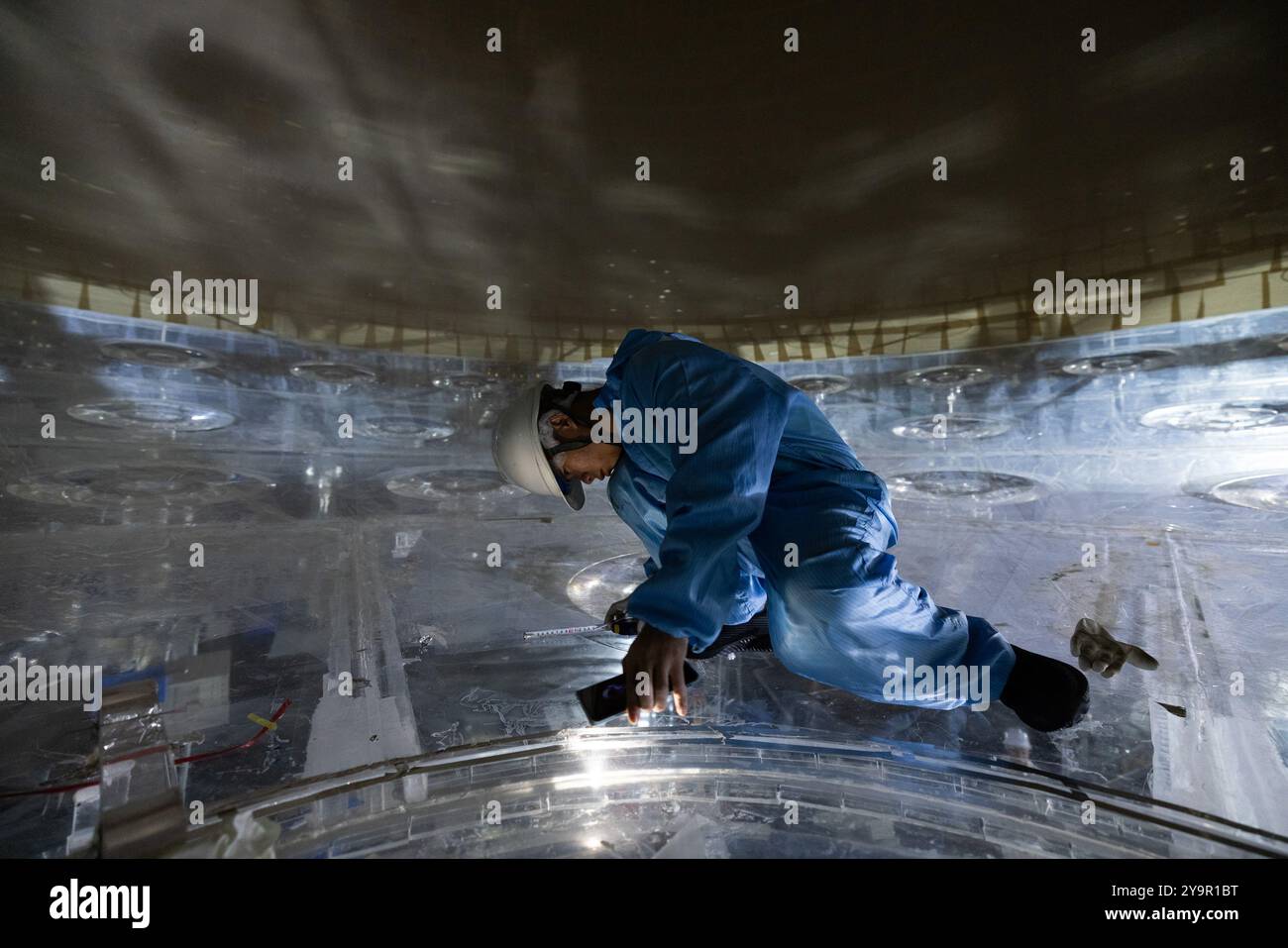 (241011) -- JIANGMEN, Oct. 11, 2024 (Xinhua) -- Un membre du personnel inspecte la sphère acrylique à l'intérieur du détecteur central de l'Observatoire souterrain de neutrinos de Jiangmen (JUNO) à Jiangmen, dans la province du Guangdong du sud de la Chine, Oct. 9, 2024. La Chine a construit le plus grand détecteur sphérique transparent du monde à 700 mètres sous terre pour capturer des neutrinos insaisissables, souvent surnommés « particules fantômes », afin de percer les secrets de l'infiniment petit et de l'infiniment vaste de l'univers. La sphère acrylique de 12 étages avec un diamètre de 35,4 mètres, enfouie profondément dans une couche de granit d'une colline à Ka Banque D'Images