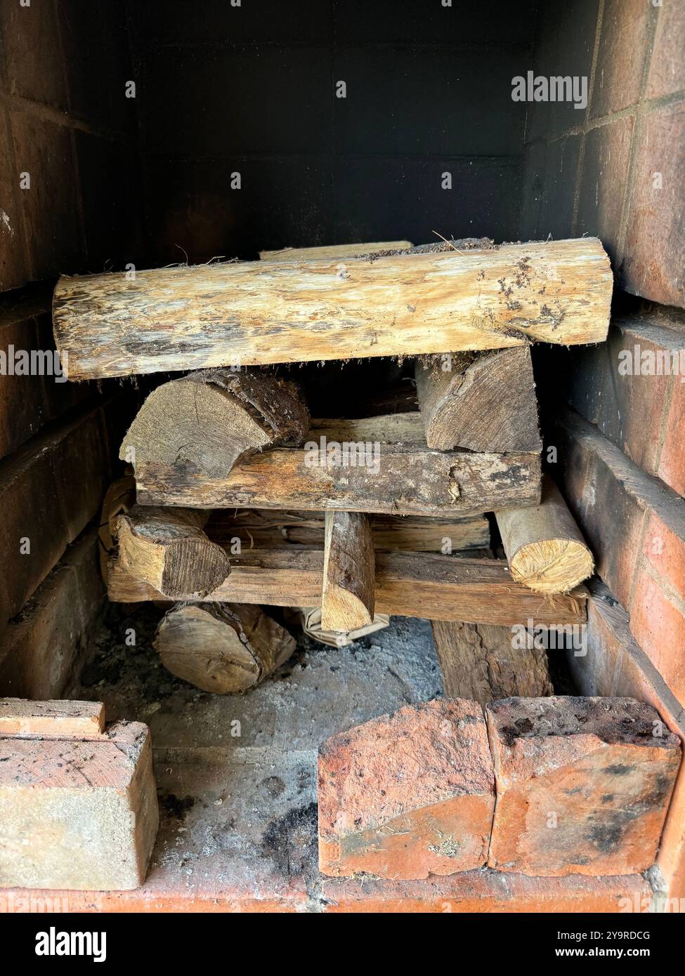 Bûches de bois de chauffage soigneusement empilées à l'intérieur d'un foyer en brique prêt à brûler. Banque D'Images