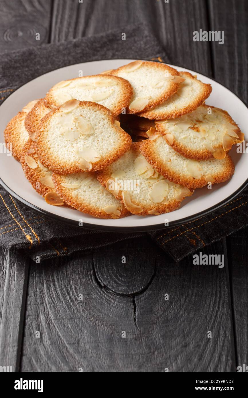 Tuiles d'amande un cookie français avec allure gros plan sur l'assiette sur la table. Vertical Banque D'Images