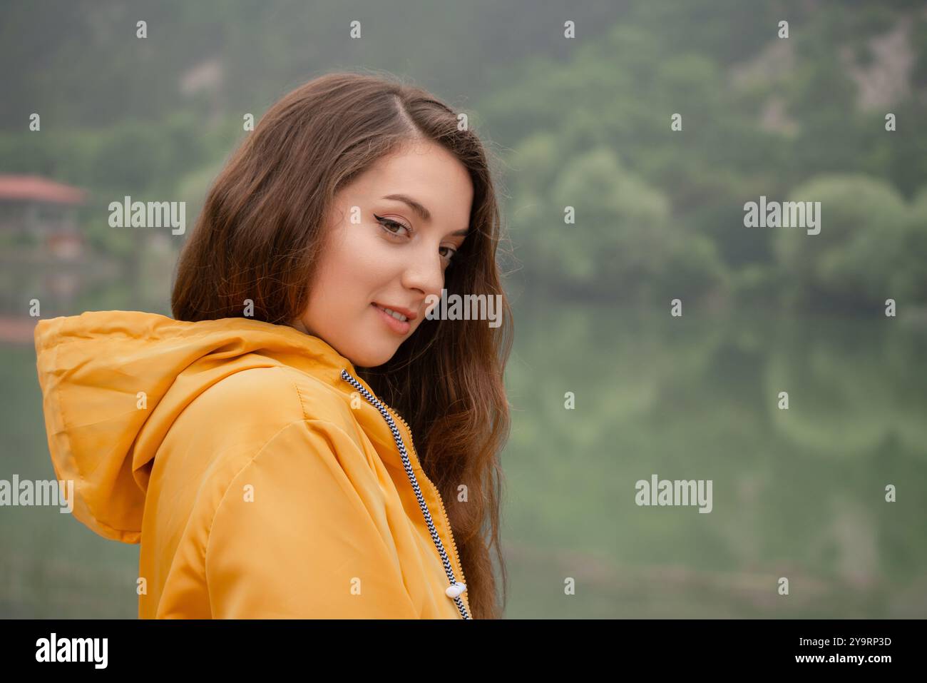 Une femme en veste jaune se tient devant un lac Banque D'Images