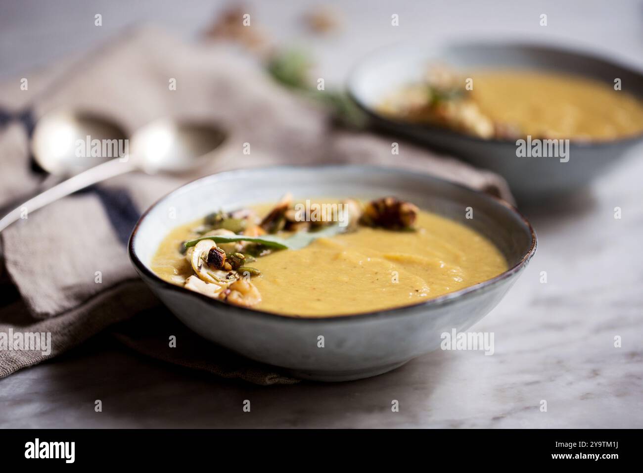 Soupe de chou-fleur rôtie servie dans deux bols en céramique grise garnie de noix de cajou grillées et de graines de citrouille. Banque D'Images Soupe de chou-fleur rôtie servie dans deux bols en céramique grise garnie de noix de cajou grillées et de graines de citrouille. Banque D'Images