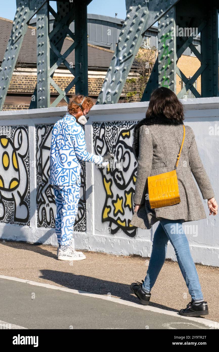 M. Doodle travaille sur sa fresque de rue ''Have a Doodley Day!' Sur Regents Park Rd Bridge Primrose Hill Camden Londres Royaume-Uni Banque D'Images