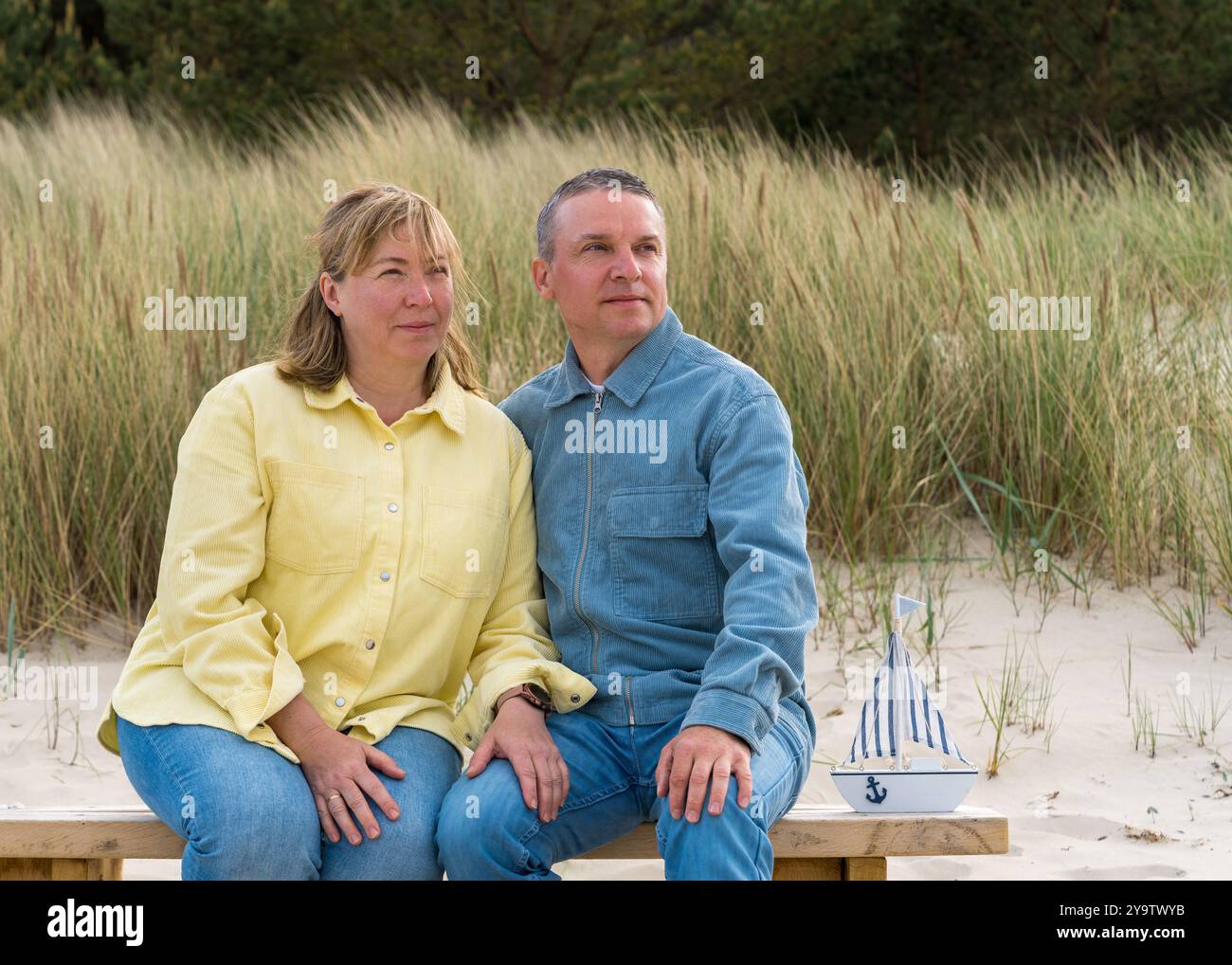 Couple adulte heureux dans l'amour assis sur le banc sur la plage. L'homme et la femme s'embrassent tendrement. Les relations familiales Banque D'Images