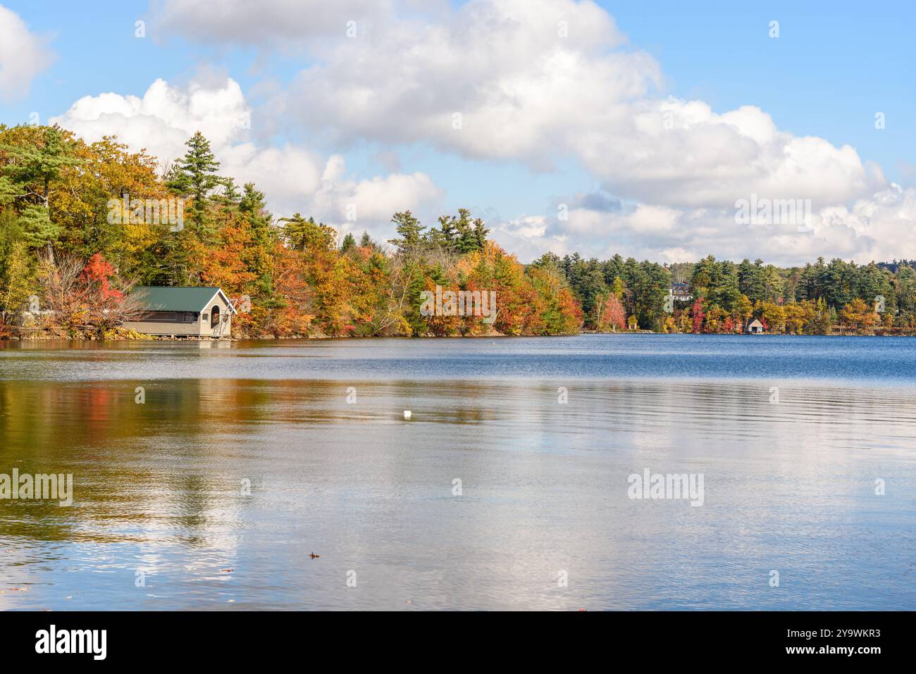 Chalets en bois sur un lac avec des rives boisées au sommet du feuillage d'automne par une journée ensoleillée Banque D'Images