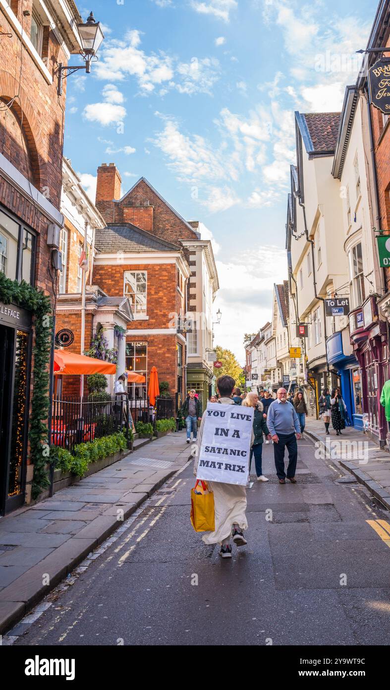 Homme marchant le long des rues étroites avec un panneau de protestation et habillé de blanc dans la ville acient de York. Banque D'Images