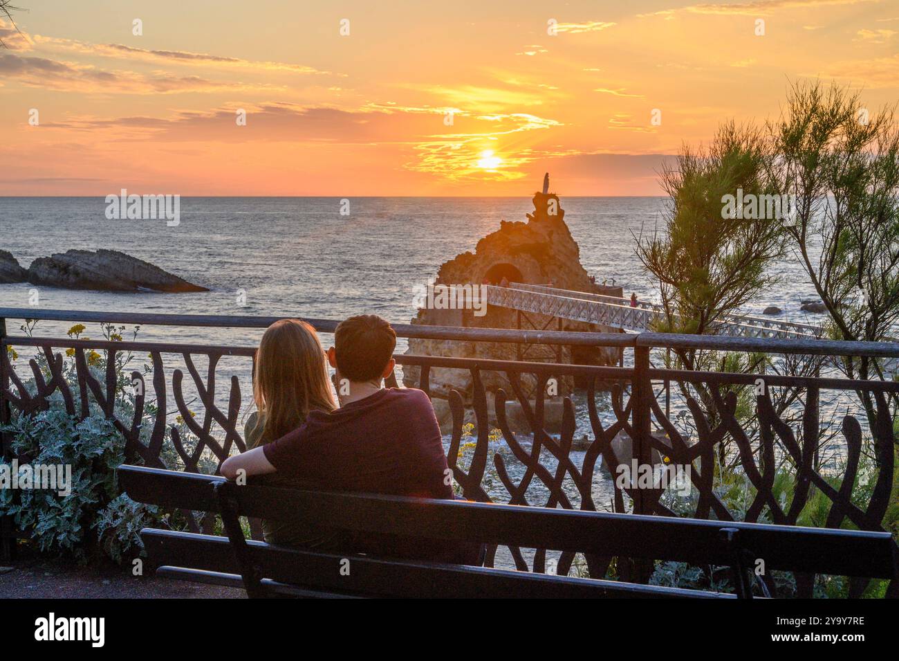 France, Pyrénées-Atlantiques (64), pays Basque, couple assis sur un banc admirant le coucher de soleil avec vue sur le rocher de la vierge Banque D'Images