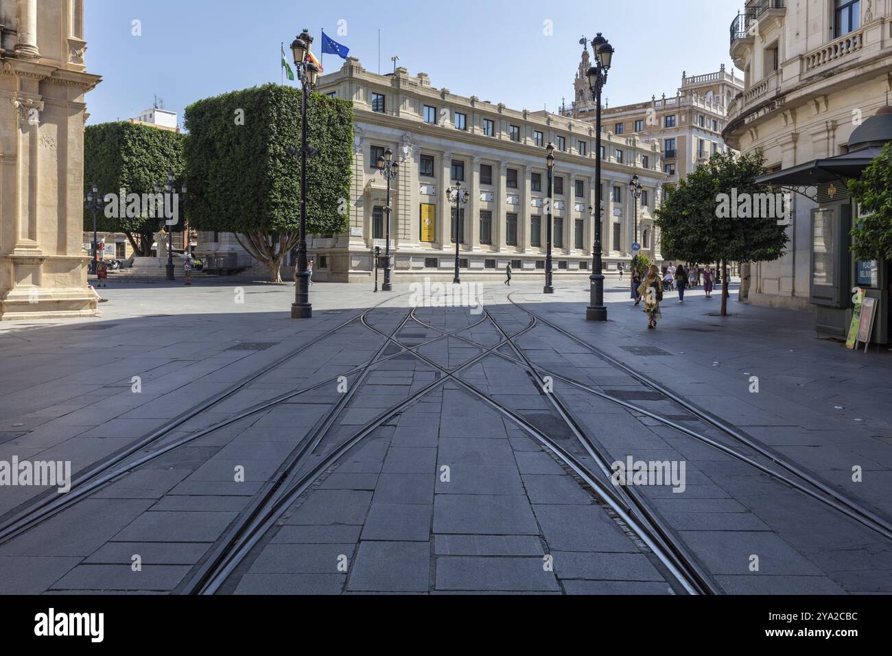 Rues vides avec des voies de tramway et des bâtiments historiques, bordés de grands arbres, Séville Banque D'Images Rues vides avec des voies de tramway et des bâtiments historiques, bordés de grands arbres, Séville Banque D'Images