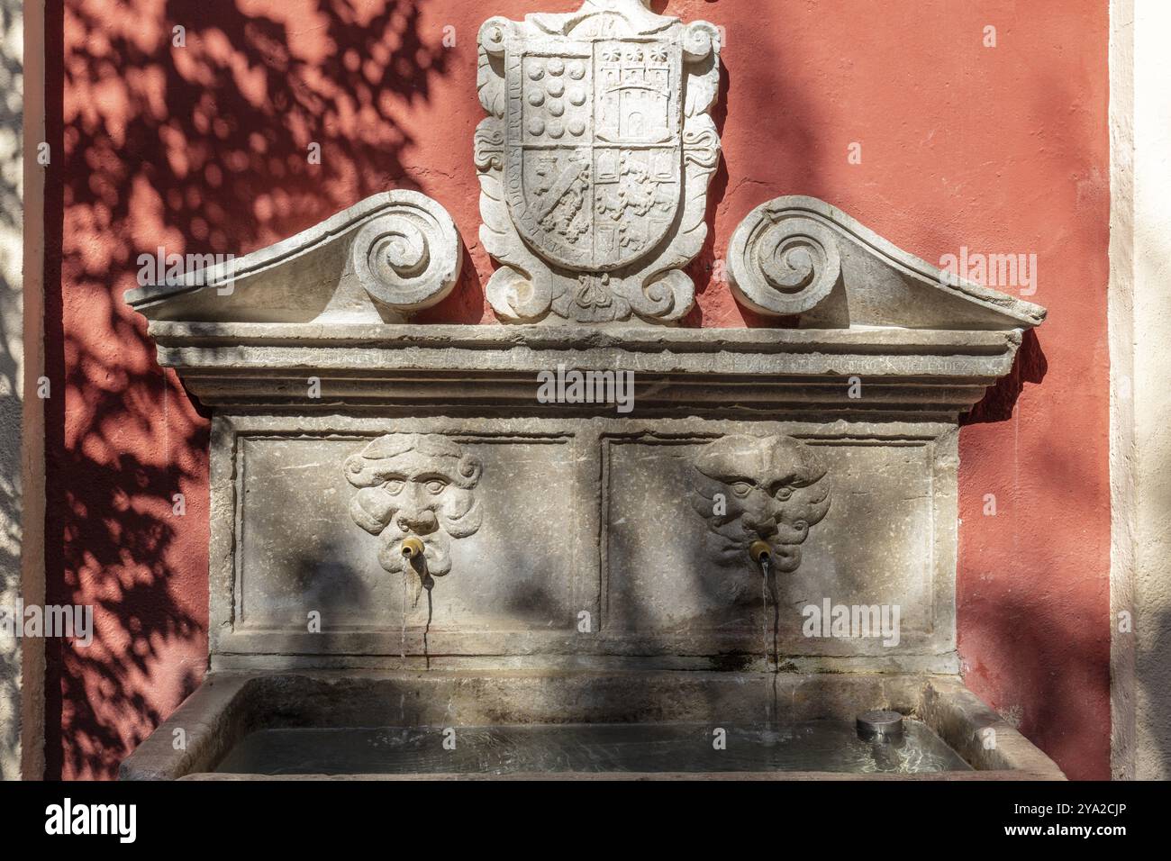 Fontaine en pierre décorée avec armoiries et motif d'eau sur fond ombragé, Grenade Banque D'Images