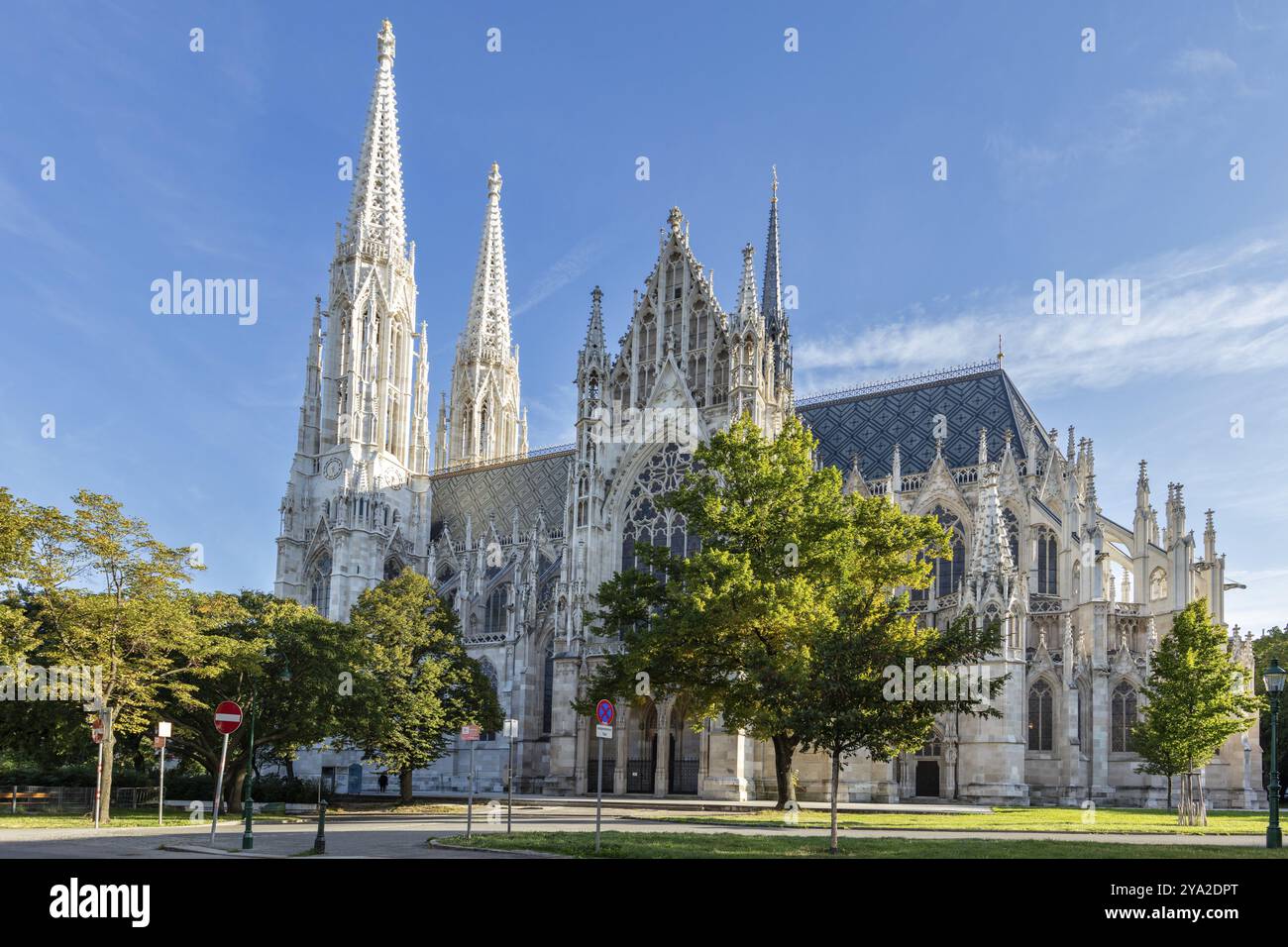 Vue latérale d'une église néo-gothique, entourée d'arbres et d'un ciel bleu, Vienne Banque D'Images Vue latérale d'une église néo-gothique, entourée d'arbres et d'un ciel bleu, Vienne Banque D'Images
