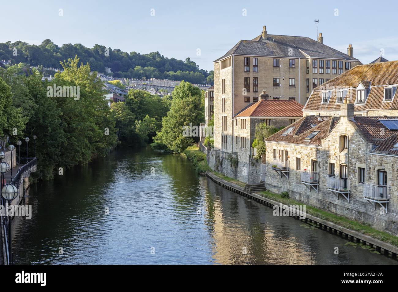 La rivière coule tranquillement à côté des bâtiments historiques et des arbres verts dans la lumière du soleil, Bath Banque D'Images La rivière coule tranquillement à côté des bâtiments historiques et des arbres verts dans la lumière du soleil, Bath Banque D'Images