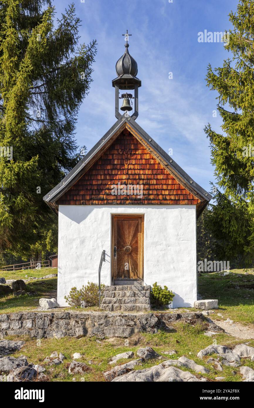 Petite chapelle en bois et pierre entourée de grands arbres sous un ciel dégagé, Winklmoosalm Banque D'Images