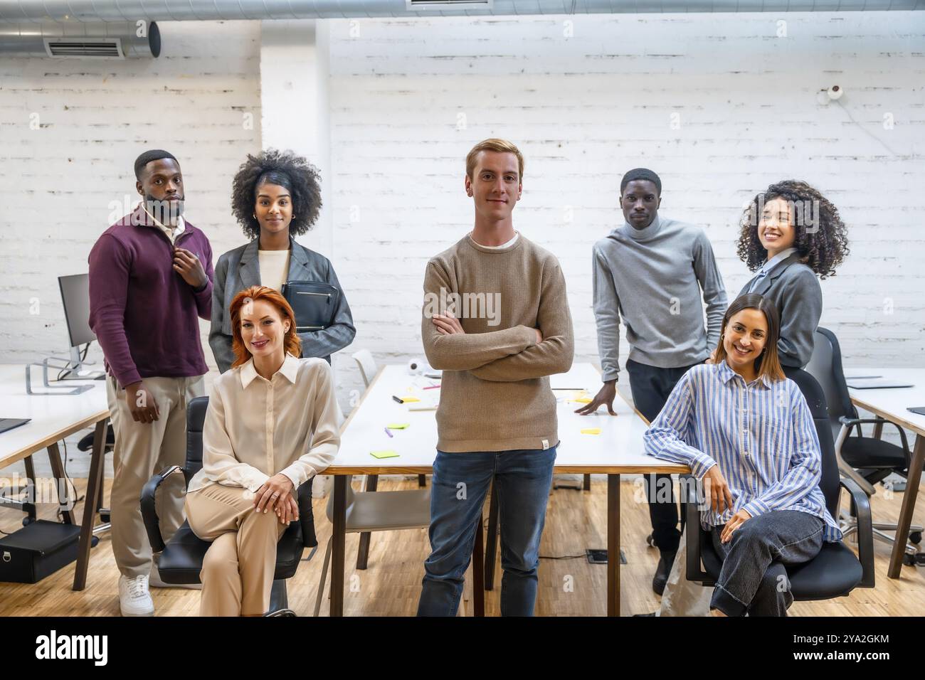 Portrait d'un homme confiant debout à côté de collègues de coworking assis autour d'une table Banque D'Images