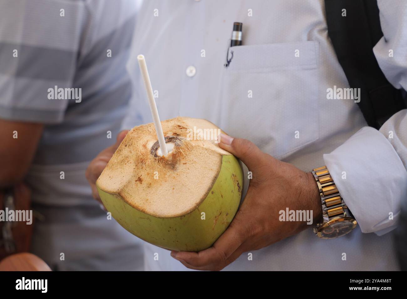 Un homme tenant une noix de coco fraîchement ouverte avec de la paille Banque D'Images