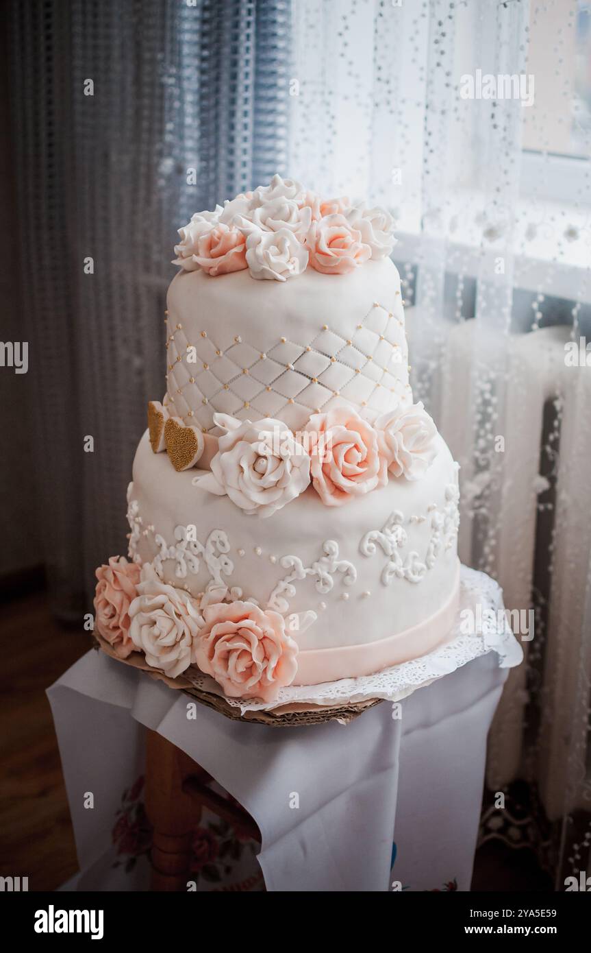 Elégant gâteau de mariage à deux niveaux orné de belles roses fondantes. Banque D'Images