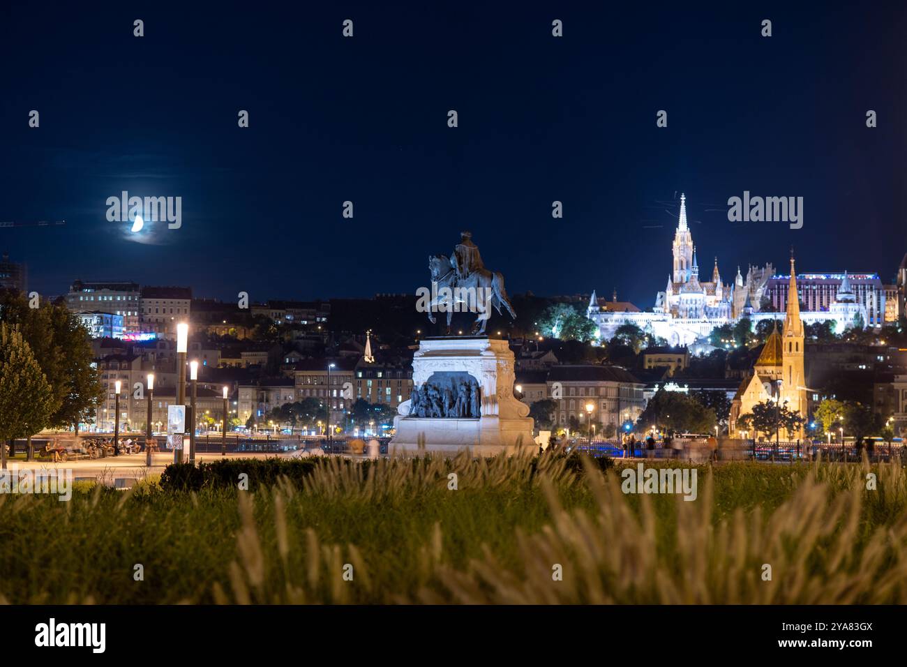 Budapest, Hongrie - 12 août 2024 : Statue du comte Gyula Andrássy la nuit. La lune et le bastion pêcheur sur le fond. Banque D'Images