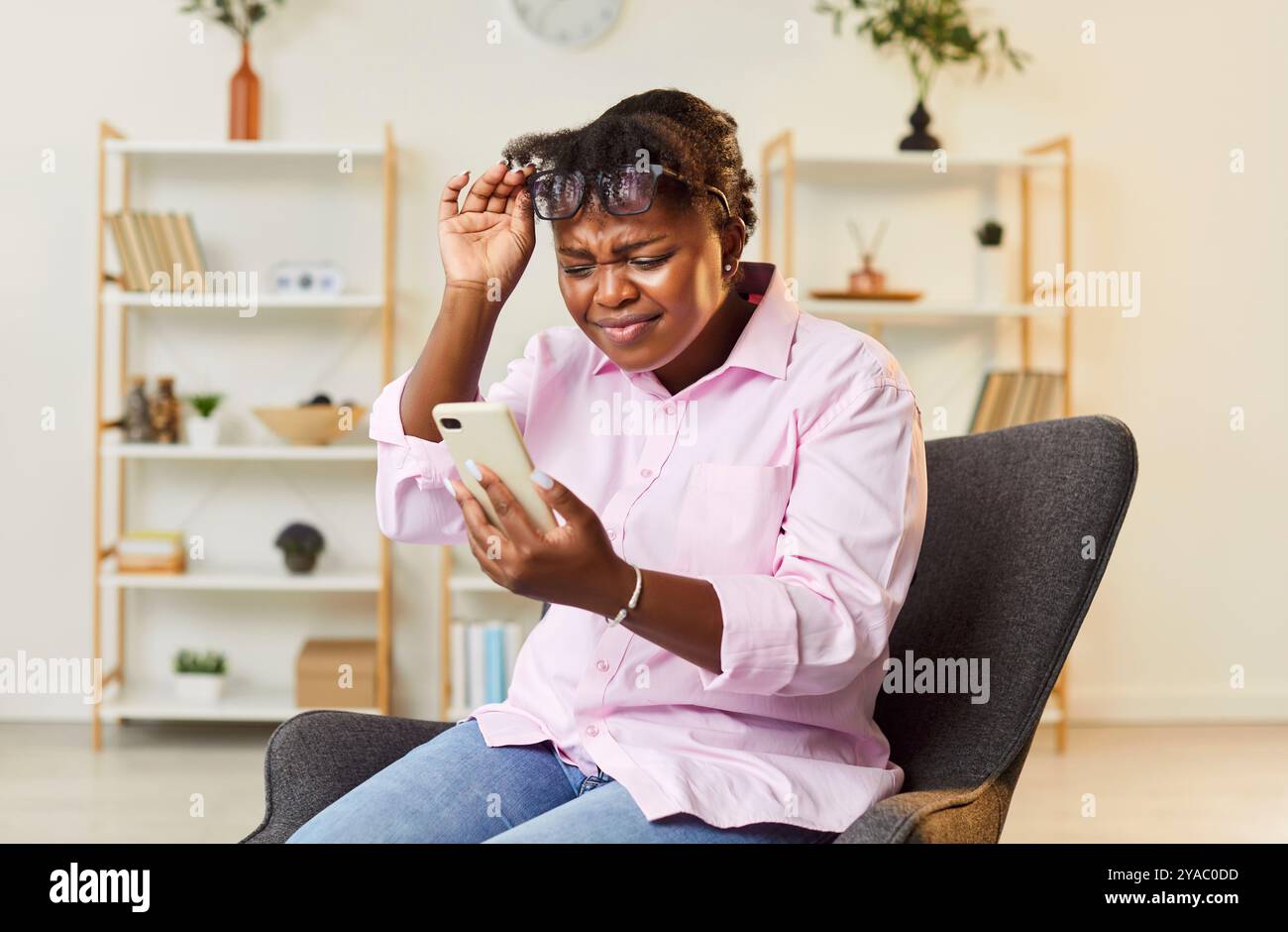 Femme afro-américaine d'âge moyen regardant un smartphone avec des lunettes vers le haut, gros plan Banque D'Images
