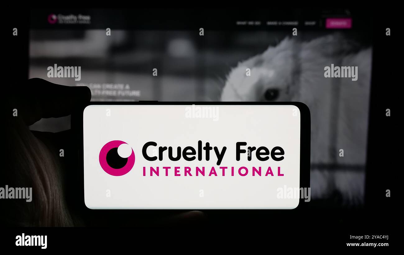 Personne tenant le téléphone portable avec le logo de l'organisation Cruelty Free International sur l'écran en face de la page Web. Concentrez-vous sur l'affichage du téléphone. Banque D'Images