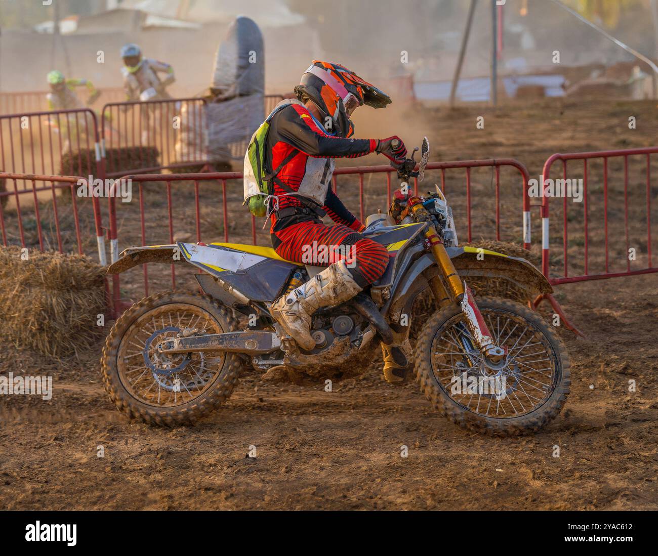 Vue latérale d'un pilote de motocross en action prenant un virage sur une piste de terre lors d'une compétition d'endurance de course de moto avec d'autres pilotes le poursuivant Ar Banque D'Images