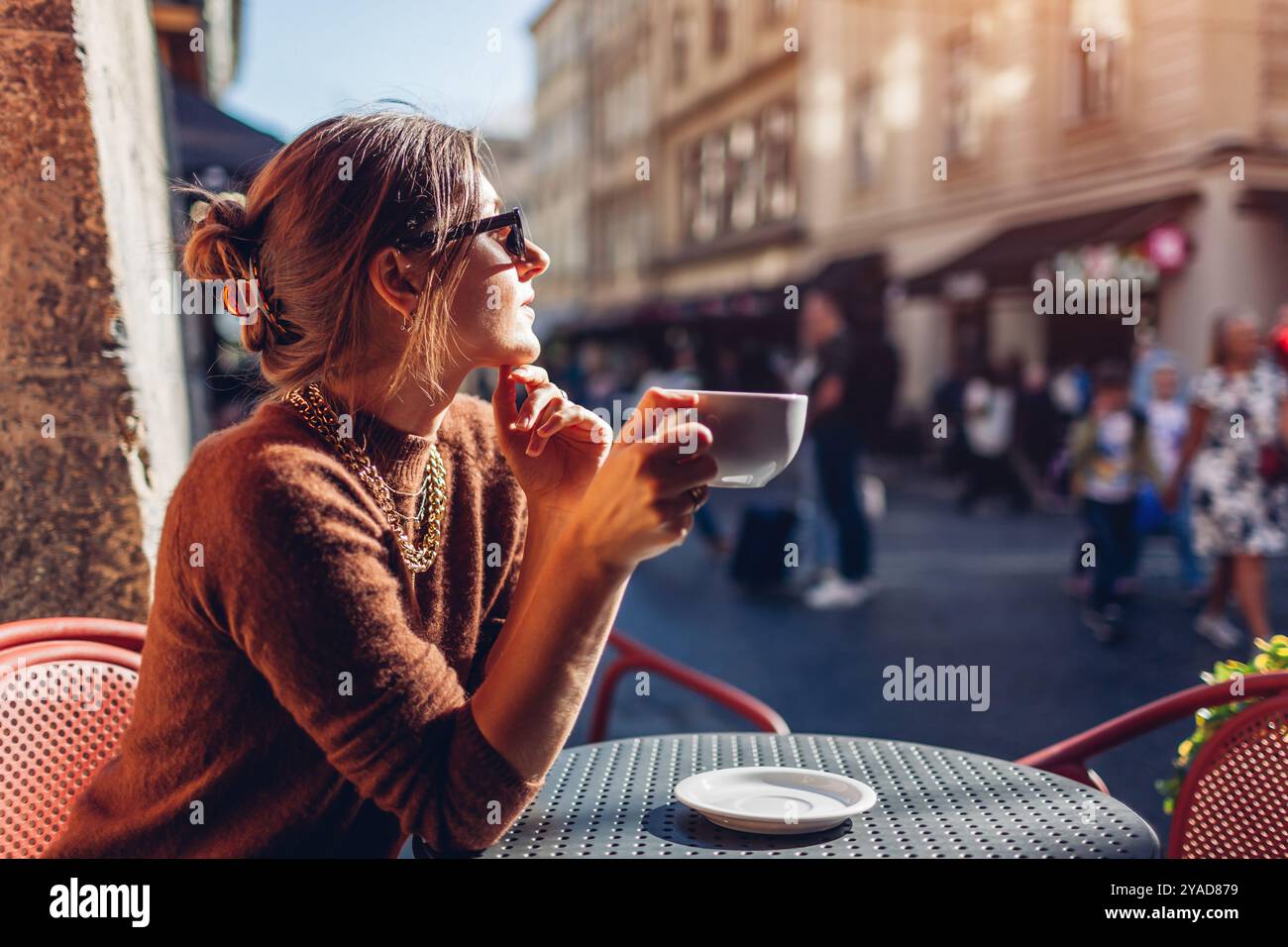 Portrait de femme élégante assise dans le café en plein air buvant du café. Femme appréciant l'architecture de la ville de Lviv sur la rue Banque D'Images