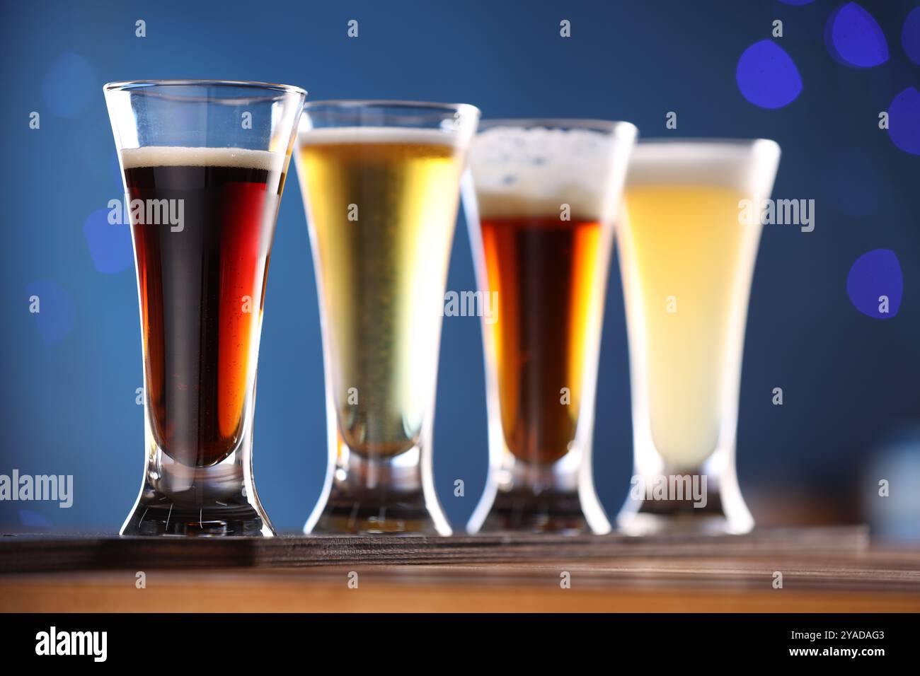 Verres avec différents types de bière sur une table en bois sur fond bleu, gros plan Banque D'Images