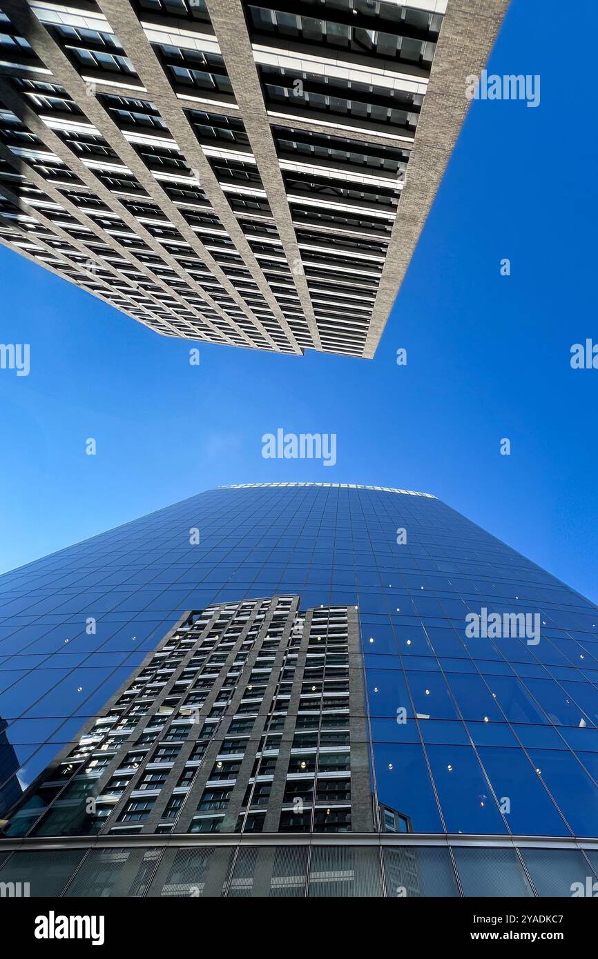 Bloc de bureaux rejeté dans les fenêtres en verre plat d'un bloc de bureaux voisin. Levant les yeux avec un ciel bleu vif. Londres, Angleterre, Royaume-Uni Banque D'Images