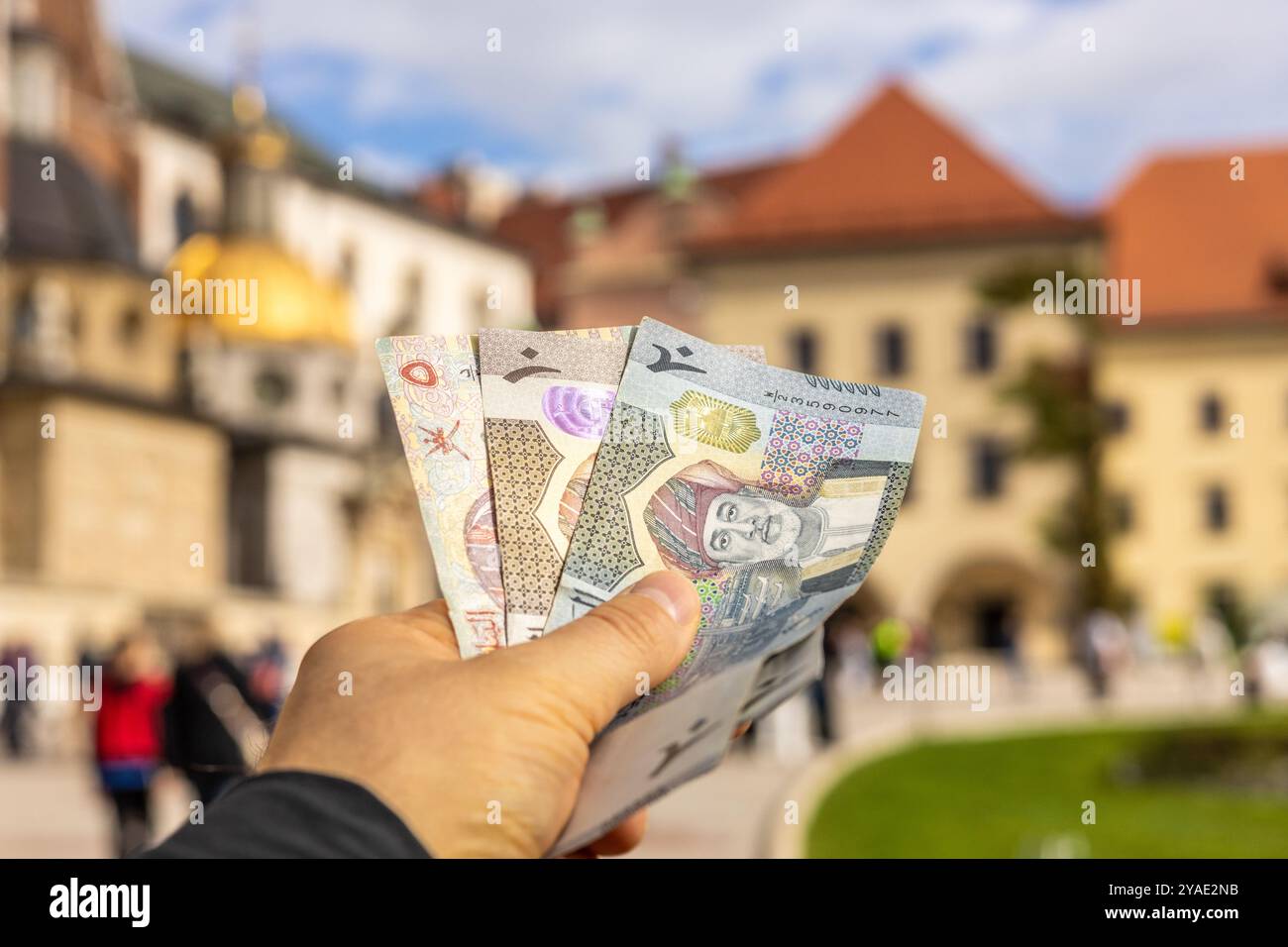 De l'argent d'Oman tenu dans la main d'un touriste devant le château de Cracovie. Voyager en Pologne et dans les pays d'Europe de l'est. Destination de voyage tendance Banque D'Images