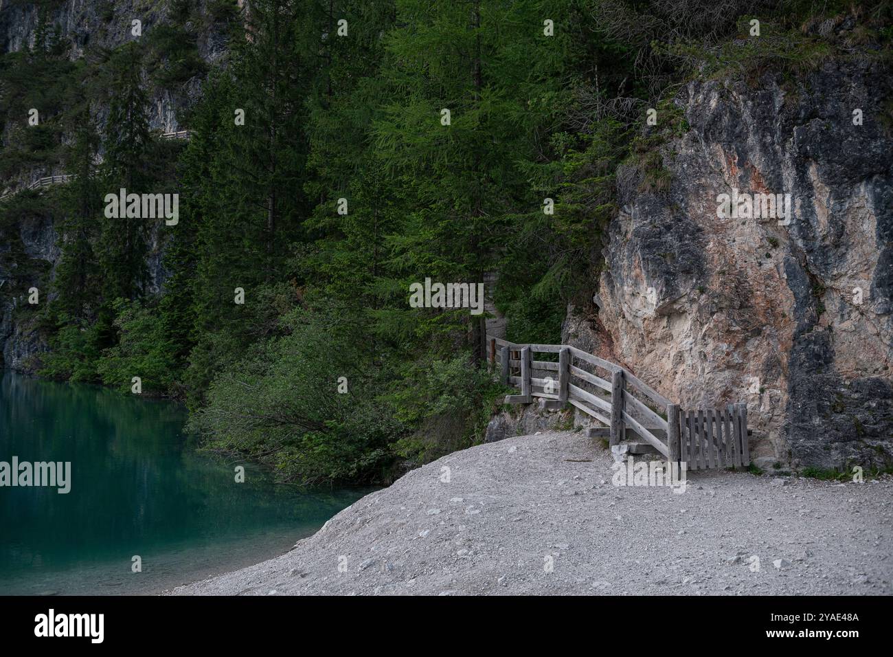 Chemin en bois le long de la face rocheuse de Pragser Wildsee, Tyrol du Sud, Italie - paisible après-midi d'été promenade au bord du lac Emeraude Banque D'Images